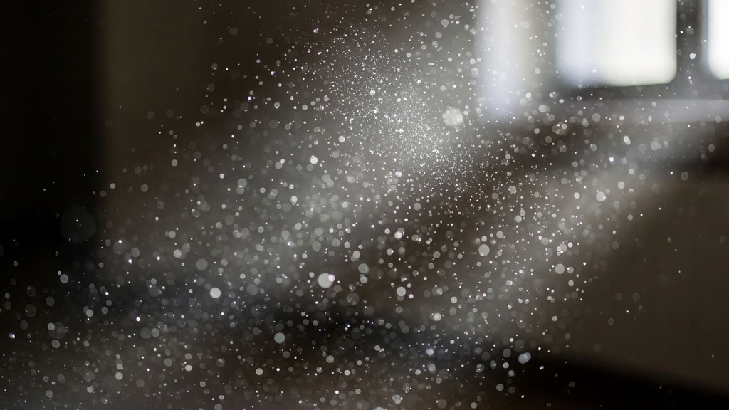 Particules de poussière industrielle visibles dans rayon de lumière atelier